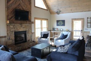 Main floor with stone  fireplace and rustic wood in chevron pattern to ceiling. 