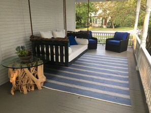 Delightful side porch with swing and two swivel chairs