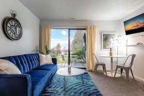 A versatile full futon sofa bed paired with a dining table for two, accompanied by a smart TV, and granting access to a charming balcony.