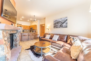 Living area with mounted flat screen TV, gas fireplace, ample seating and balcony access.