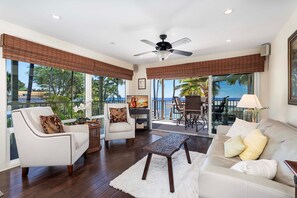 Living room with views of the ocean, sofa, armchair, ceiling fan, and smart TV