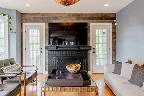 Comfortable L-shaped couch, two stylish chairs, 75-in flat-screen TV, fireplace.