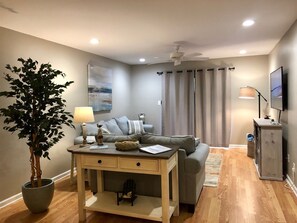 Living room with large flat screen and cable.  Several books, games and movies.