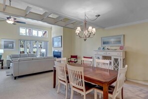 - Host memorable meals at this charming wood dining table with seating for six under a classic chandelier
- Soft yellow walls and beach themed décor enhance the relaxing ambiance
- Open view into the cozy living room keeps the conversation flowing