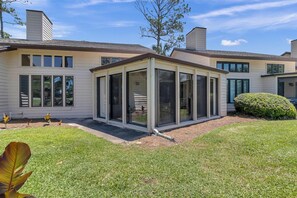 Bright enclosed sunroom extends your living space with scenic garden and yard views.