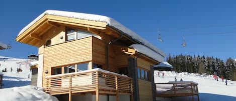 chalet viewed from the roadside with ski slope behind