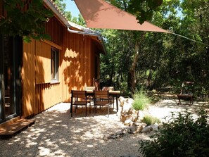 La terrasse de l'Ecogîte à l'ombre des chênes et de la voile solaire.