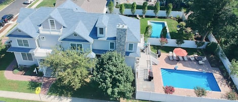 Drone view of the house, showing the yard with the porch, paver patio, and pool.