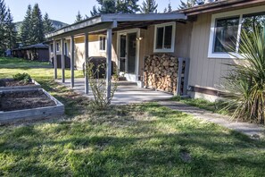 Back covered patio with propane gas grill and firewood for inside wood stove.