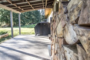 Back covered patio with propane gas grill and firewood for inside wood stove.