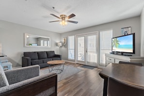 Living Room looking out to patio - French doors, wood flooring, large flat screen television and updated furnishings add to the ambiance at 108 Grand Caribbean West.