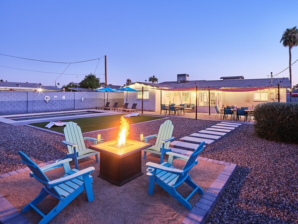 Private backyard with a pool, fire pit, corn hole, sun loungers, BBQ grill, and multiple seating areas.