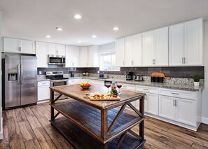 Fully-equipped kitchen with stainless steel appliances, basic cooking essentials, and a big kitchen island.