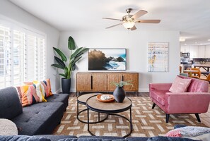 Bright living room with designer decor, multiple seating, and smart TV.