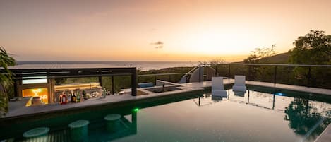 Sunset over the swim-up bar and pool sun shelf