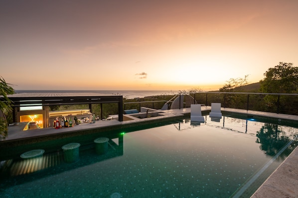 Sunset over the swim-up bar and pool sun shelf