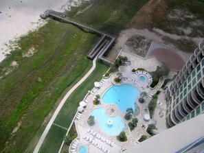 View from balcony of pools, hot tub and walkway to beach