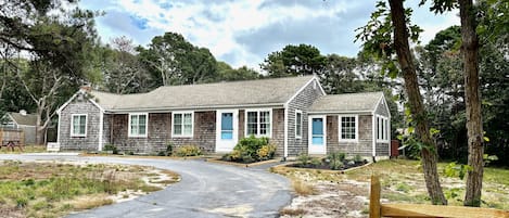 Front view of the cape cottage with a circular driveway