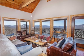 Great Room at Divine View with Designer Furniture and a Wall of Windows Which Frame Mountain Views