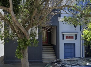 Front of Building.  There are about 8 steps up from the street to the main level.   Apartment is on the main level. Bedroom window is behind the tree in this photo