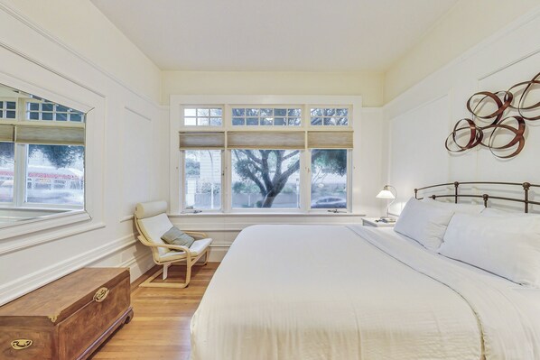 The bedroom with queen-sized bed looks out onto a lovely tree-lined street.