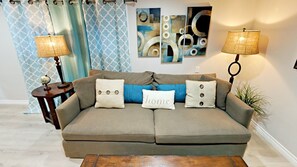 Living Room with wall mounted Cable TV, comfy Down Feather Sofa, Pottery Barn coffee table, and end table.