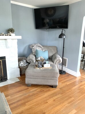 Living room with over sized chair, ottoman, big screen TV and ample seating. 