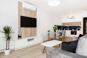 A spacious living room with a TV mounted on the wall, modern decor, and white furniture for a clean look.
