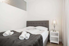 Another bedroom featuring a cozy bed with white bedding and a simple, minimalist decor style.