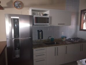 Cozinha com geladeira inox, microondas e Cooktop