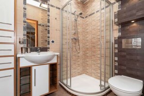 A bathroom with a shower, modern fixtures, and neutral tiles. The clean design offers both style and functionality.