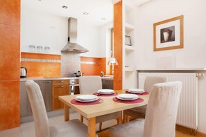 A close-up of the dining table set for a meal, with red accents adding a pop of color against the warm wooden tones.