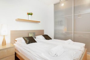 A cozy bedroom with a double bed, soft linens, and modern decor. The room has a serene, minimalist feel.