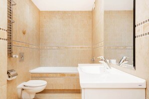 A stylish bathroom with a bathtub, modern sink, and neutral-toned tiles. Clean and functional.