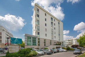 An exterior view of the apartment building, showcasing its modern architecture and surrounding greenery.