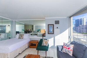 Comfortable queen bed and living area with views of the city & mountains