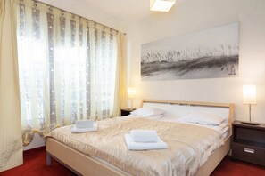 A cozy bedroom with a double bed, bedside lamps, and access to a balcony, perfect for fresh air and a view of the surroundings.
