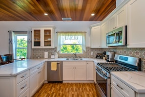 Kitchen with gas stove, built in microwave oven, quartz countertop, dishwasher.