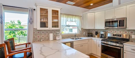 Kitchen with quartz countertop, dishwasher, gas stove and red cedar ceiling