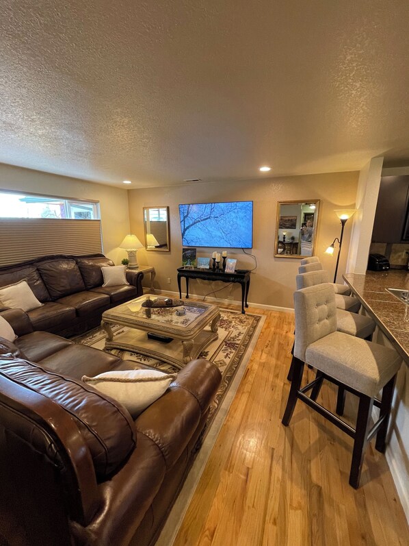 Open floorplan between fully stocked kitchen and living room with four barstools
