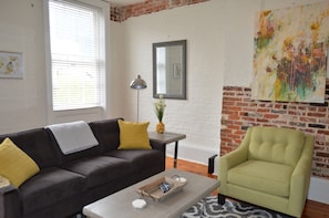 Living Room has a sofa sleeper, plenty of original exposed brick
