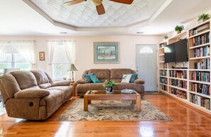 A portion of Great Room, shows double & triple reclining couches, library, & TV