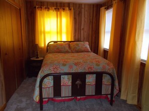 Double Bed with Chest and Nightstand with Lamp.  Antique Room.  Lots of Windows.