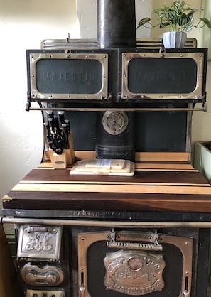 An antique wood stove serves as the kitchen island with a handcrafted wood top.