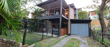 Front of house showing secure fence, yard, garage and top deck.