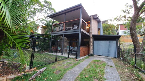 Front of house showing secure fence, yard, garage and top deck.