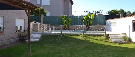 Jardín  trasero con la piscina, chiscón don barbacoa y celador
