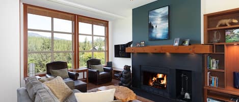 Spacious yet cozy living area with large windows and expansive views of the Chateau Whistler Golf Course