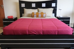 Queen size bed in Queen room appointed with a rug, closet, night lamps & linens