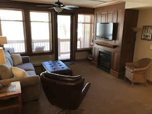 Open living room with gas fireplace, flat screen  TV -opens onto private balcony